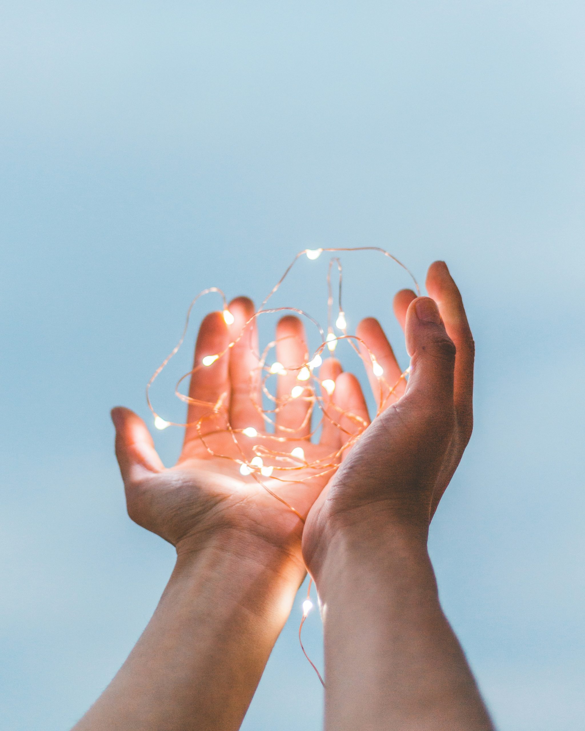 Mains tenant une guirlande lumineuse – illustration de l’énergie lumineuse transmise par le Reiki